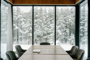 a room with chairs around a table and large windows